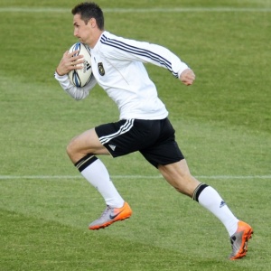 Miroslav Klose corre carregando bola de rgbi durante treinamento da seleo alem