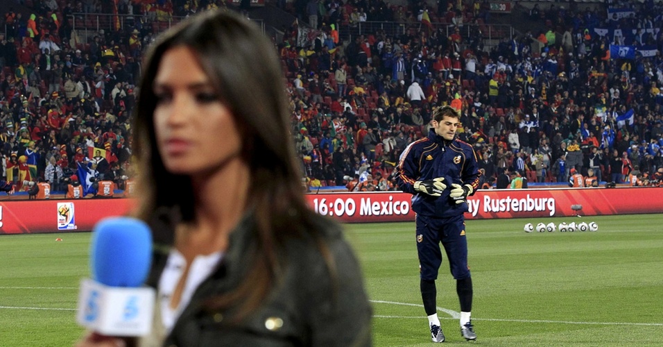 21.jun.2010 - Jornalista Sara Carbonero faz passagem para a TV tendo ao fundo seu namorado, o goleiro da Espanha Iker Casillas, durante aquecimento para jogo da Copa do Mundo