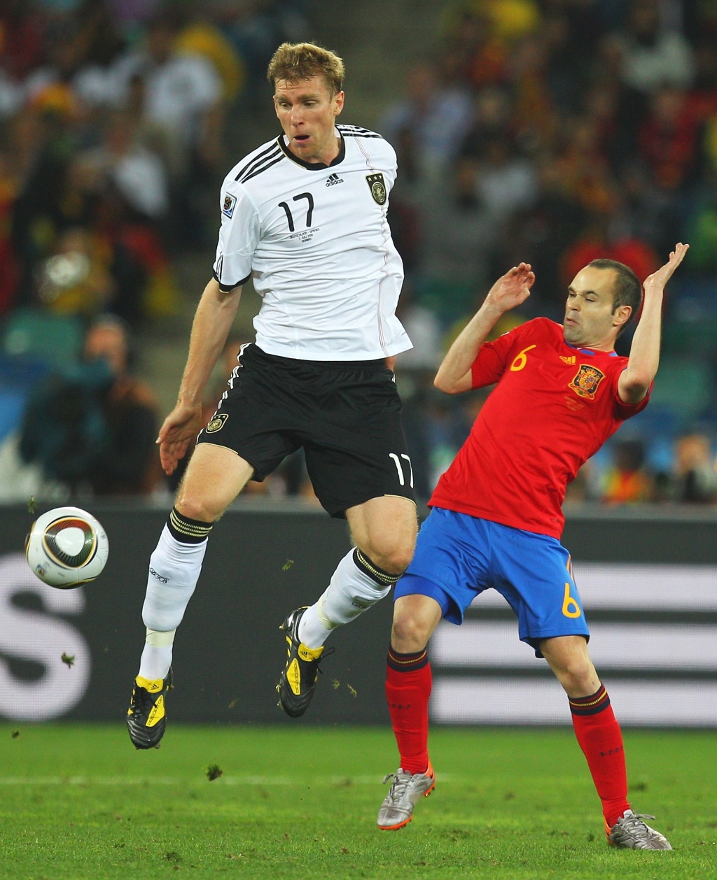 Mertesacker (e) disputa a bola com Iniesta no jogo Alemanha x Espanha