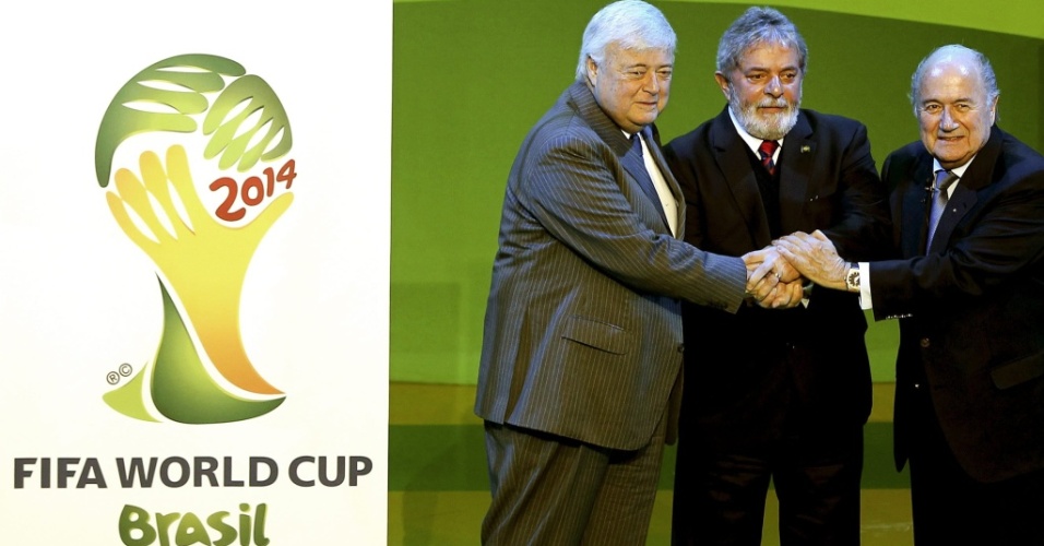 Ricardo Teixeira, Lula e Joseph Blatter cumprimentam-se ao lado da logomarca da Copa de 2014