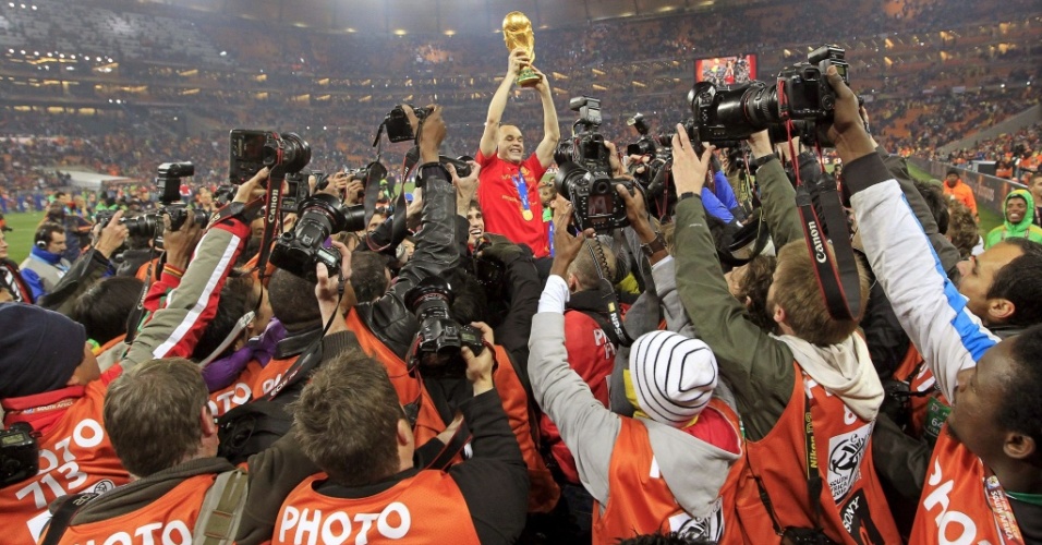 Herói do título espanhol, Iniesta é cercado por jornalistas enquanto ergue a taça Fifa